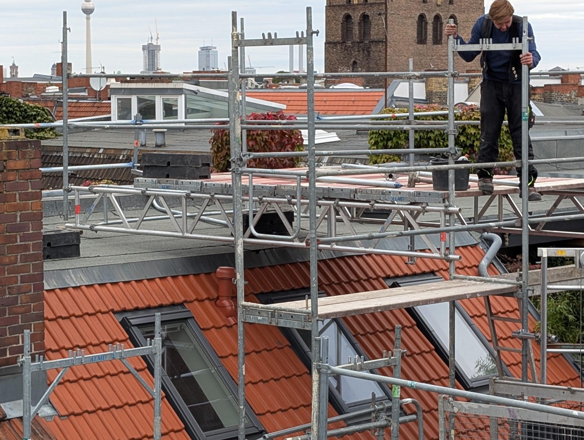 Handwerker auf Gerüst mit Blick auf Berliner Skyline